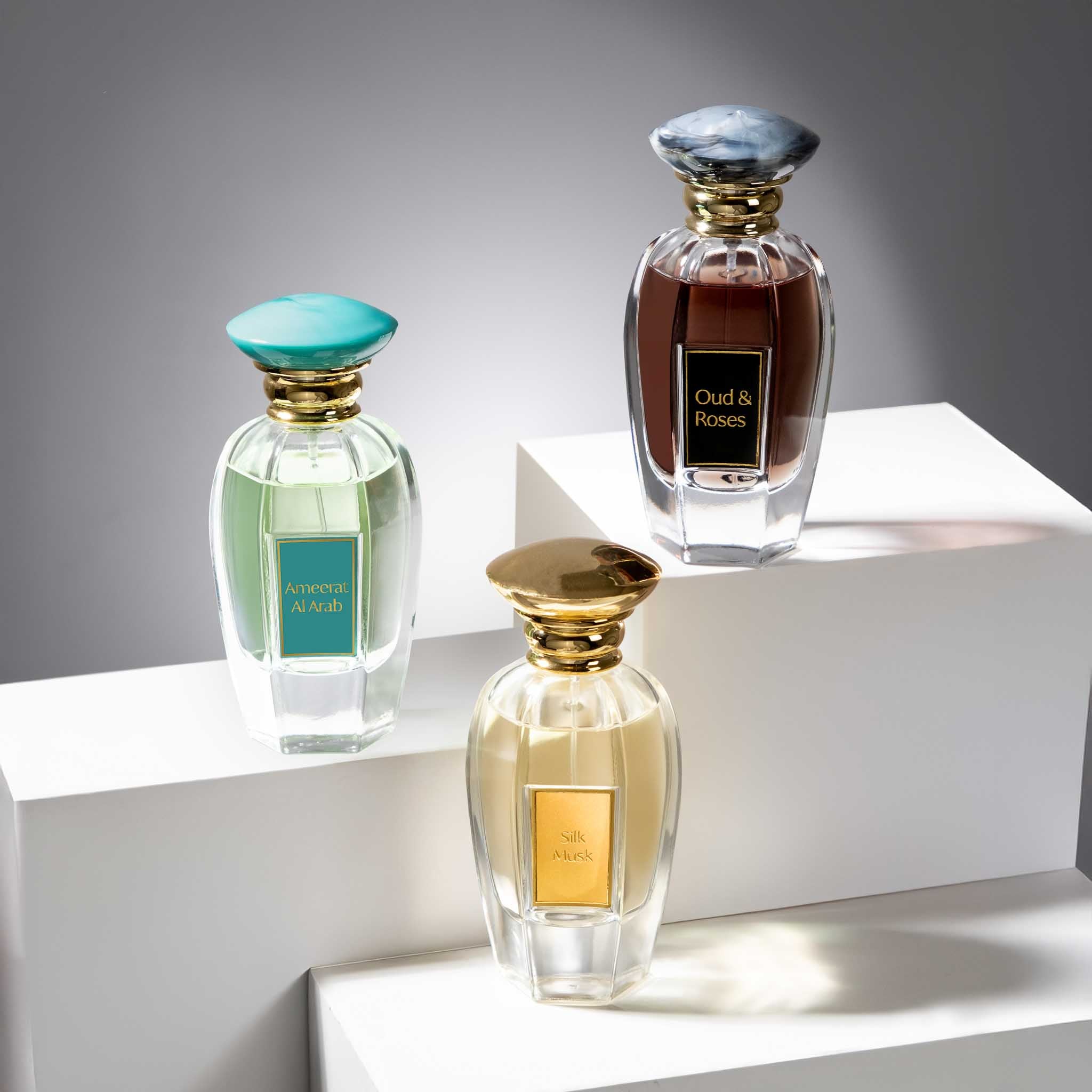 Three perfume bottles on a white surface with a gray background
