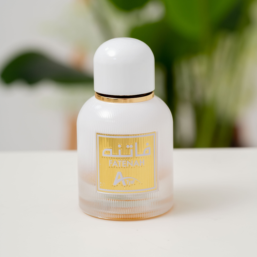 Perfume bottle with a white cap and gold label on a blurred green background