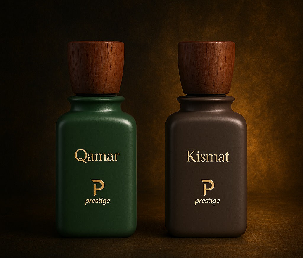 Two perfume bottles labeled 'Qamar' and 'Kismat' with wooden caps on a dark background.