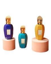 Three colorful perfume bottles on stands with visible labels against a white background