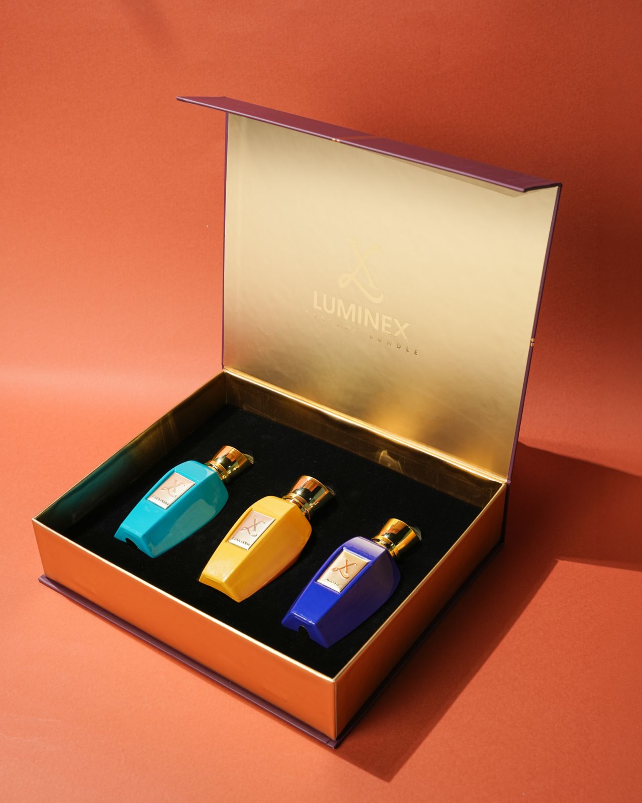 Three small bottles of perfume in a Luminex box on an orange background