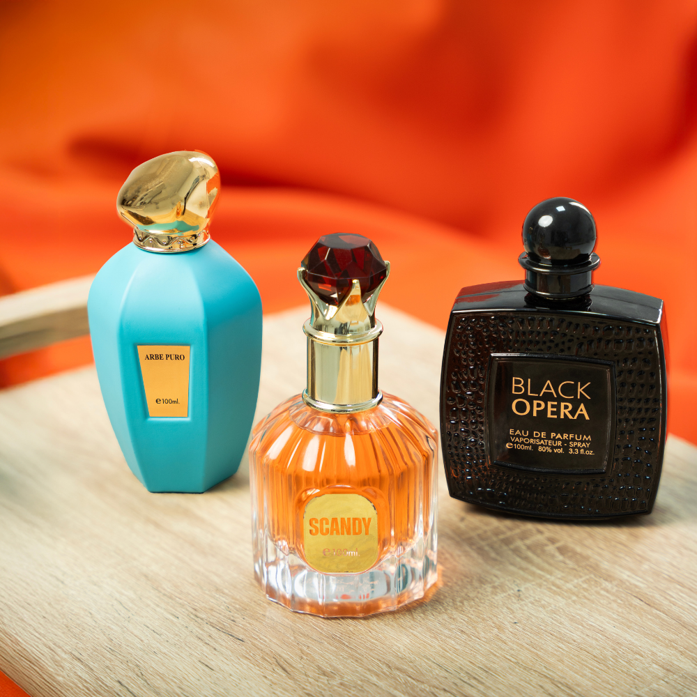 Three perfume bottles on a wooden surface with an orange background