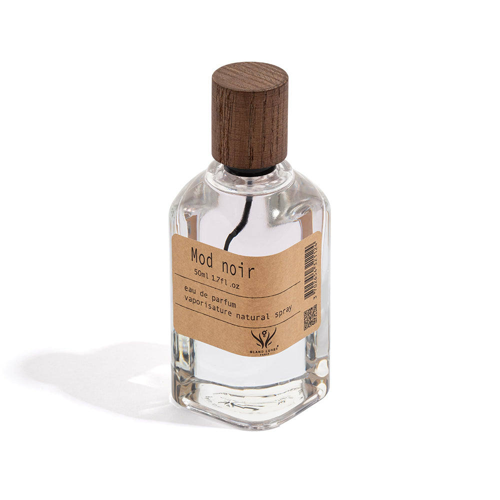Clear perfume bottle with wooden cap and 'Mod Noir' label on a white background