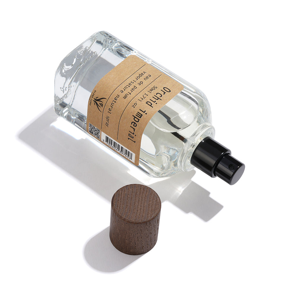 Clear glass perfume bottle with wooden cap on a white background