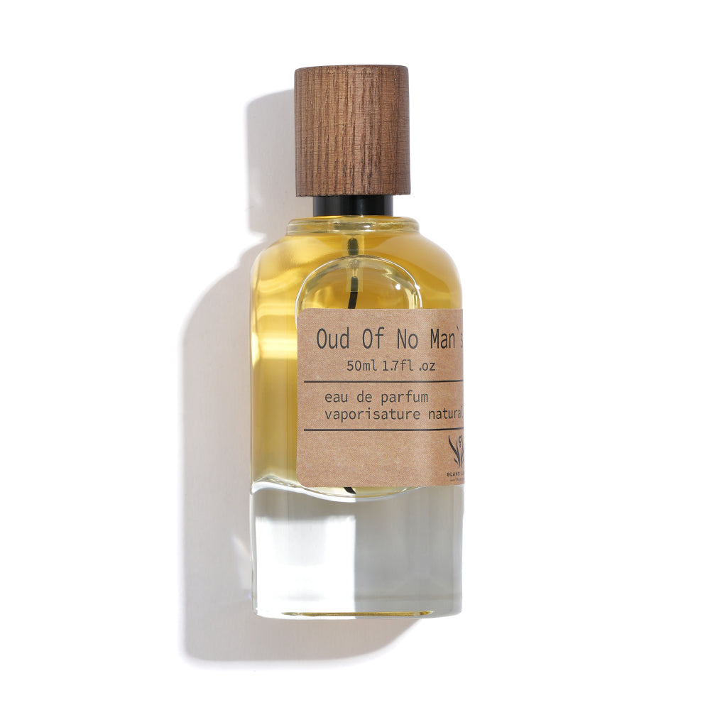 Perfume bottle labeled 'Oud Of No Man' with wooden cap on a white background