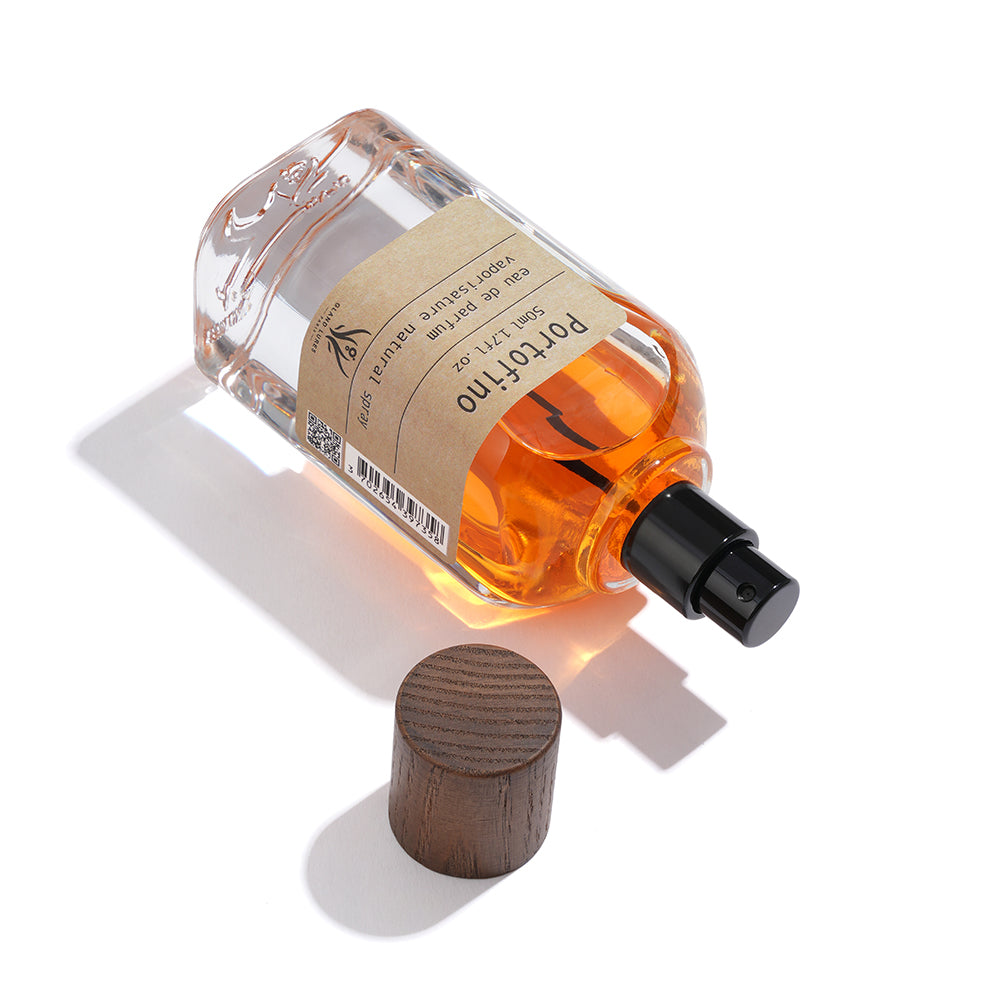 Amber-colored perfume bottle with wooden cap on a white background